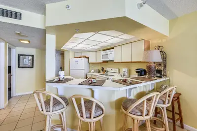 a kitchen with a counter and chairs in a room at Summerhouse 710B by Book That Condo in Panama City Beach