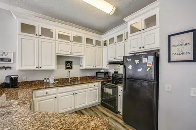 a kitchen with white cabinets and a black refrigerator at C Dreams by Book That Condo in Panama City Beach