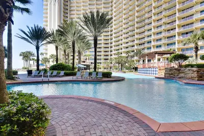 a swimming pool in a resort with palm trees and buildings at Shores of Panama #1627 by Book That Condo in Panama City Beach