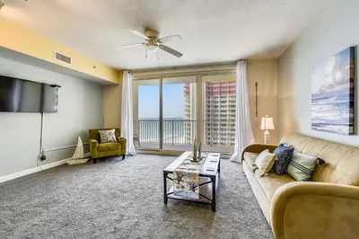 a living room with a couch and a tv at Shores of Panama #1627 by Book That Condo in Panama City Beach