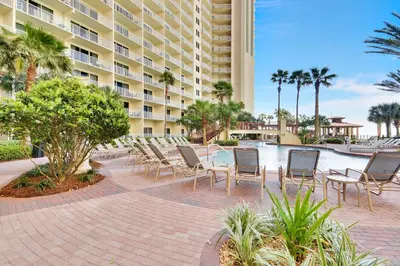 a patio with chairs and a table in front of a building at Shores of Panama #1627 by Book That Condo in Panama City Beach