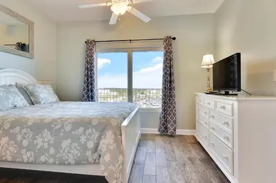 a bedroom with a bed and a television and a window at Shores of Panama #624 by Book That Condo in Panama City Beach