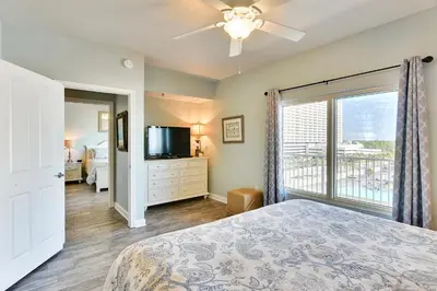 a bedroom with a bed and a tv and a window at Shores of Panama #624 by Book That Condo in Panama City Beach