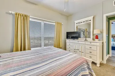 a bedroom with a bed and a dresser with a television at Shores of Panama #1007 by Book That Condo in Panama City Beach