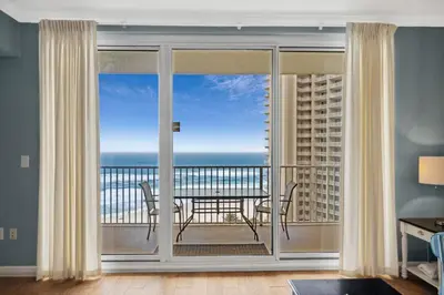 a living room with a view of the ocean from a balcony at Shores of Panama #1119 by Book That Condo in Panama City Beach