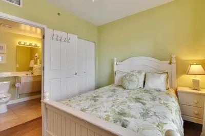 a bedroom with a white bed and a bathroom at Shores of Panama #1421 by Book That Condo in Panama City Beach