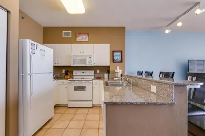 a kitchen with a white refrigerator and appliances at Shores of Panama #1421 by Book That Condo in Panama City Beach