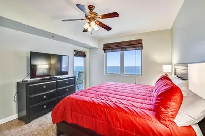 a bedroom with a red bed and a flat screen tv at Shores of Panama #1531 by Book That Condo in Panama City Beach