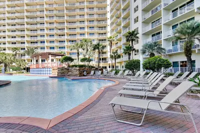 a pool with lounge chairs and a large building at Shores of Panama #1531 by Book That Condo in Panama City Beach