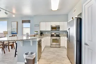 a kitchen with white cabinets and a counter top at Shores of Panama #2201 by Book That Condo in Panama City Beach