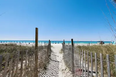 a fence on a beach with the ocean in the background at Long Beach Resort #1300-1 by Book That Condo in Panama City Beach