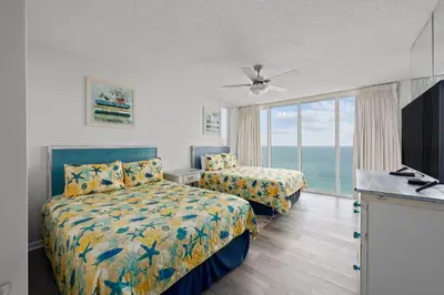 a bedroom with two beds and a window with the ocean at Long Beach Resort #1300-1 by Book That Condo in Panama City Beach