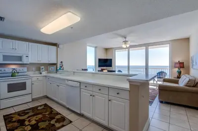 a kitchen with white cabinets and a view of the ocean at Majestic Beach Resort #1215-1 by Book That Condo in Panama City Beach
