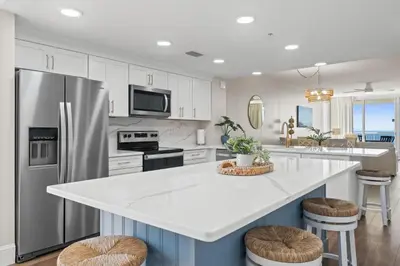 a kitchen with a refrigerator and a counter with stools at Majestic Beach Resort #1309-2 by Book That Condo in Panama City Beach