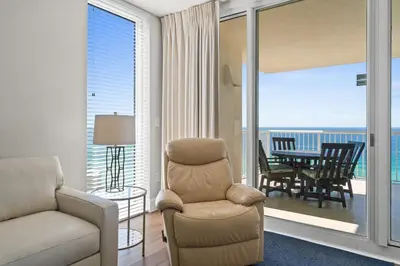 a living room with a couch and a chair and a balcony at Majestic Beach Resort #1309-2 by Book That Condo in Panama City Beach