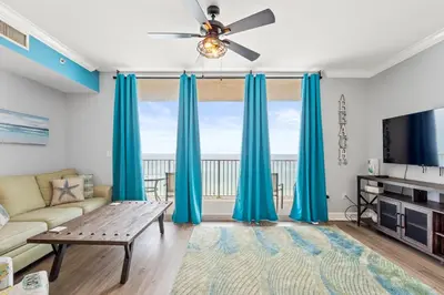 a living room with blue curtains and a couch at Tidewater Beach Resort #614 by Book That Condo in Panama City Beach