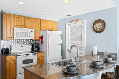 a kitchen with a white refrigerator and a sink at Splash Beach Resort #1503-E by Book That Condo in Panama City Beach