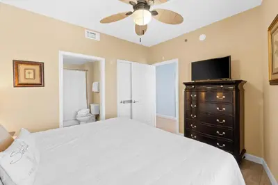 a bedroom with a bed with a ceiling fan and a television at Splash Beach Resort #1503-E by Book That Condo in Panama City Beach