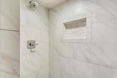 a white bathroom with a shower with white marble walls at Pinnacle Port #115A by Book That Condo in Panama City Beach