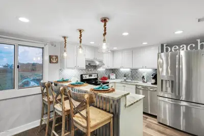 a kitchen with white cabinets and a kitchen island with chairs at Pinnacle Port #115A by Book That Condo in Panama City Beach
