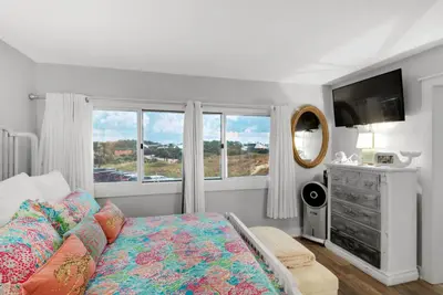 a bedroom with a bed and a tv and windows at Pinnacle Port #115A by Book That Condo in Panama City Beach