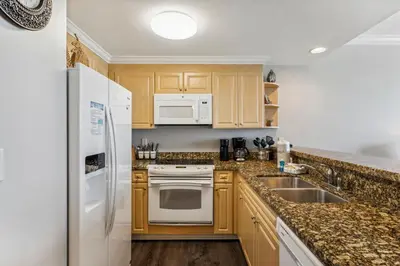 a kitchen with wooden cabinets and white appliances at Boardwalk Beach Resort #806 by Book That Condo in Panama City Beach