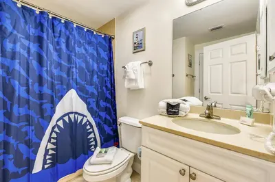 a bathroom with a blue shark shower curtain and a toilet at Boardwalk Beach Resort #1605 by Book That Condo in Panama City Beach
