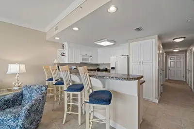 a kitchen and living room with a bar and chairs at Boardwalk Beach Resort #1703 by Book That Condo in Panama City Beach