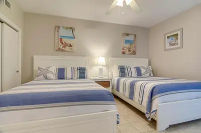 two beds in a bedroom with white and blue sheets at Boardwalk Beach Resort #1802 by Book That Condo in Panama City Beach
