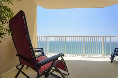 a red rocking chair on a balcony with a view of the ocean at Boardwalk Beach Resort #1802 by Book That Condo in Panama City Beach