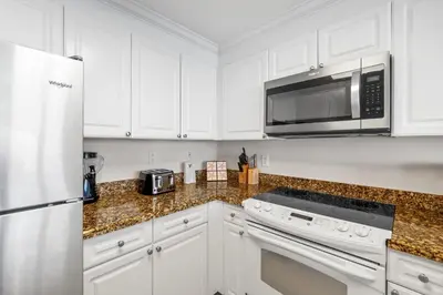 a kitchen with white cabinets and a microwave at Boardwalk Beach Resort #1909 by Book That Condo in Panama City Beach