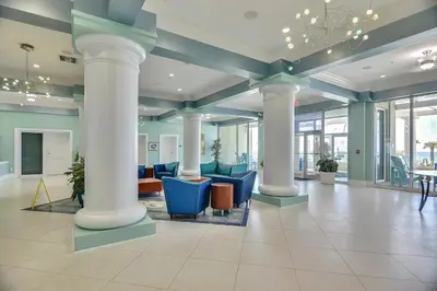 a lobby with blue chairs and columns in a building at Boardwalk Beach Resort #1909 by Book That Condo in Panama City Beach