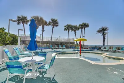 a pool with blue chairs and a table with an umbrella at Boardwalk Beach Resort #1909 by Book That Condo in Panama City Beach
