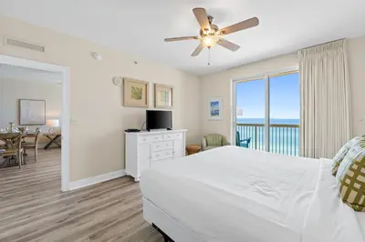 a bedroom with a white bed and a dining room at Calypso Resort and Towers #801-W by Book That Condo in Panama City Beach