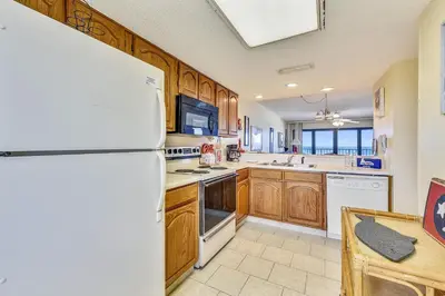 a kitchen with a white refrigerator and wooden cabinets at Commodore Resort #703 by Book That Condo in Panama City Beach