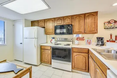 a kitchen with white appliances and wooden cabinets at Commodore Resort #703 by Book That Condo in Panama City Beach