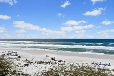 a beach with chairs and the ocean on a sunny day at Commodore Resort #703 by Book That Condo in Panama City Beach