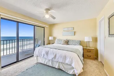 a bedroom with a bed and a balcony with the ocean at Commodore Resort #703 by Book That Condo in Panama City Beach
