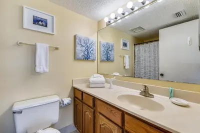 a bathroom with a sink and a toilet and a mirror at Commodore Resort #704 by Book That Condo in Panama City Beach