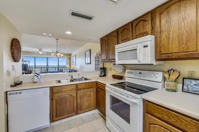 a kitchen with white appliances and wooden cabinets at Commodore Resort #704 by Book That Condo in Panama City Beach