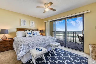a bedroom with a bed and a balcony at Commodore Resort #704 by Book That Condo in Panama City Beach