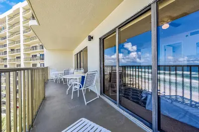 a balcony with a table and chairs and a view of the ocean at Commodore Resort #704 by Book That Condo in Panama City Beach