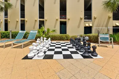 a chess board on a patio with two chairs and a building at Emerald Beach #636 by Book That Condo in Panama City Beach