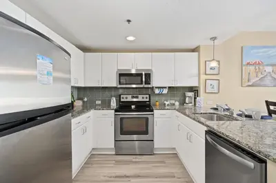 a kitchen with white cabinets and a stove top oven at Grand Panama Beach Resort #1707-1 by Book That Condo in Panama City Beach