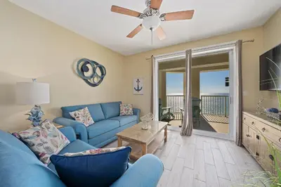 a living room with a blue couch and a ceiling fan at Grand Panama Beach Resort #1707-1 by Book That Condo in Panama City Beach