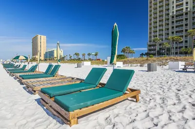 a row of chaise lounges on the beach at Grand Panama Beach Resort #1707-1 by Book That Condo in Panama City Beach