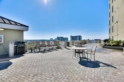 a patio with tables and chairs on a building at Grand Panama Beach Resort #1707-1 by Book That Condo in Panama City Beach
