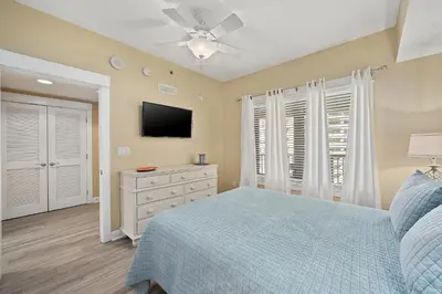 a bedroom with a blue bed and a flat screen tv at Grand Panama Beach Resort #1707-1 by Book That Condo in Panama City Beach