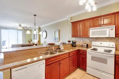 a kitchen with wooden cabinets and white appliances at Ocean Villa Condos #801 by Book That Condo in Panama City Beach