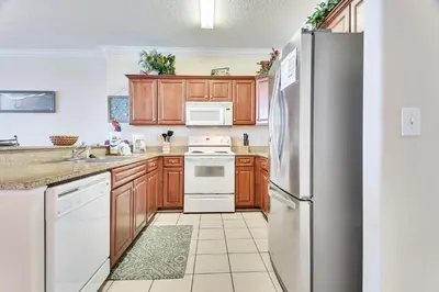a kitchen with white appliances and wooden cabinets at Ocean Villa Condos #1801 by Book That Condo in Panama City Beach